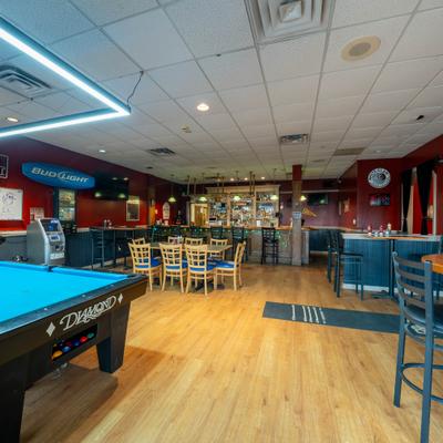 A casual sports bar interior featuring a pool table and wooden flooring.
