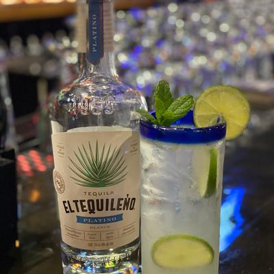 Blanco tequila bottle, cocktail with lime and mint.