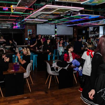 Interior, crowd  gathered under colorful ceiling lights.