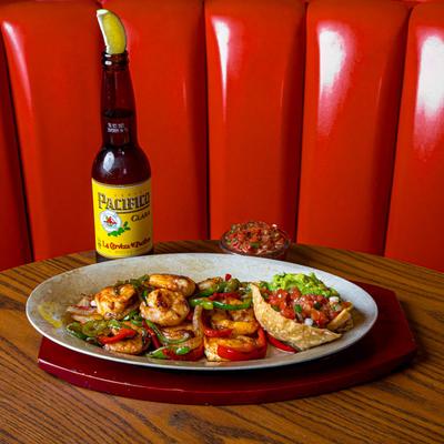 Shrimp fajitas served with a beer and a side of fresh salsa.