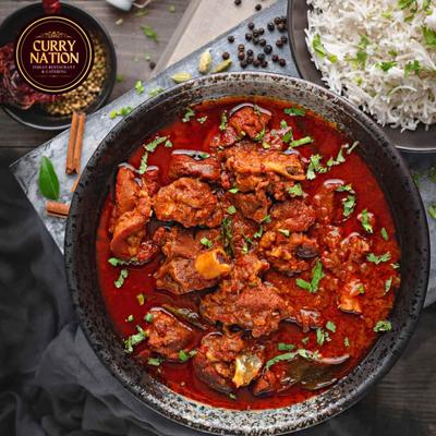 Red goat curry served served with basmati rice on the side.