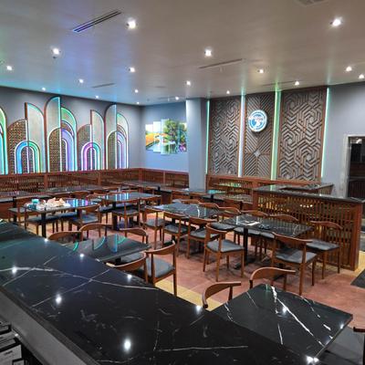 Interior with black marble tables, wooden chairs and blue neon accent lighting.