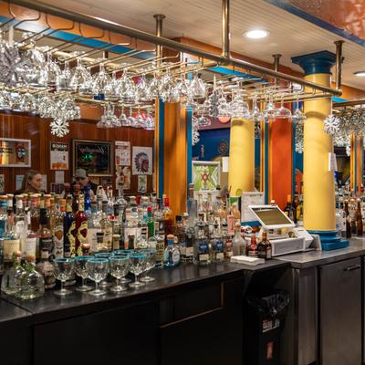 Colorful bar area with liquor, glassware, and a POS machine.