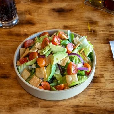 Salad bowl with lettuce, avocado, cherry tomatoes, red onion and tortilla chips.