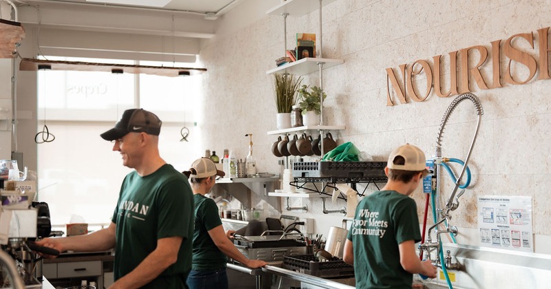 Three staff members working behind the bar counter