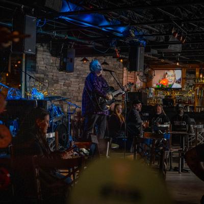 A guitar player is performing on a stage in front of audience.