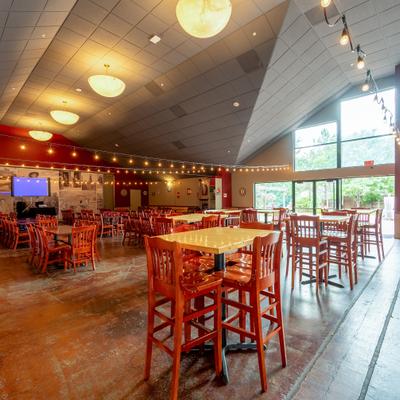 Dining hall with high-top seating, string lights, and tall windows.