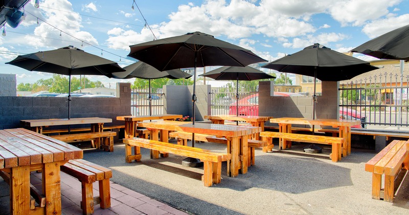 Outdoor seating area, wooden tables with benches and black parasols