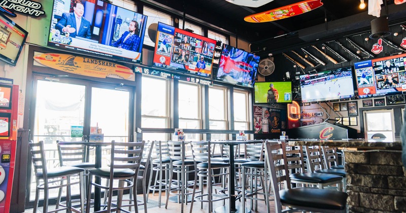 Interior, seating area, high seating tables with stools, large shop window, TVs on the walls