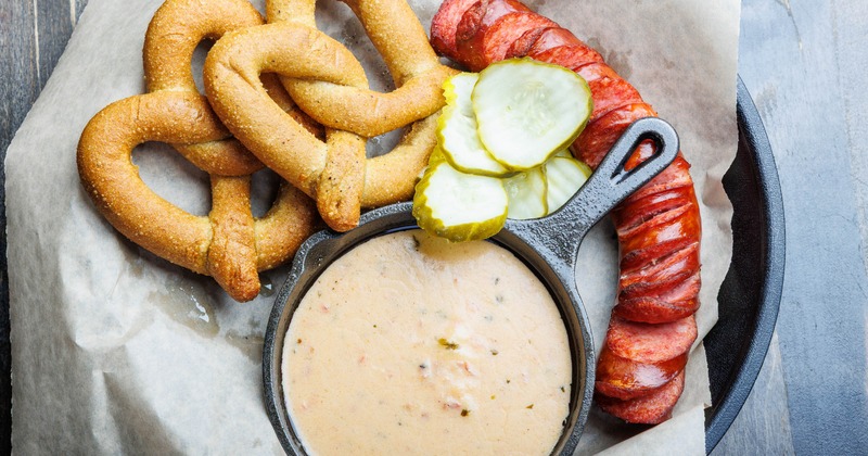Fondue Skillet served with sausage, sliced pickles and pretzels