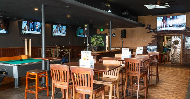 Interior, high seating tables with stools, billiards tables in the back, TVs on the walls