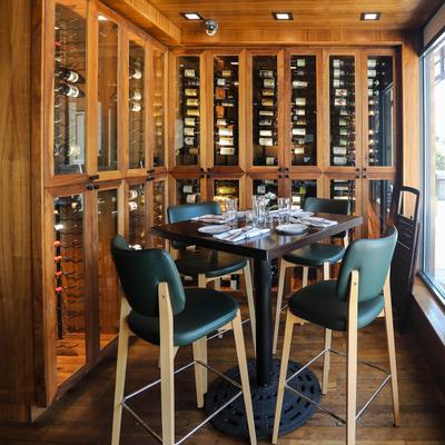 A table for four with tableware on it, in a room with wine cabinets.