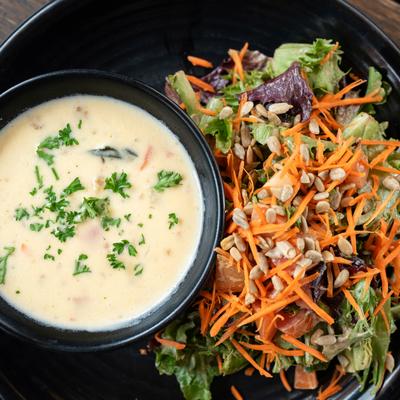 Bowl of soup served with mixed salad on the side.