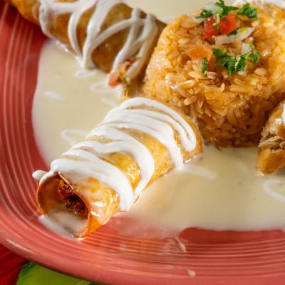 Chimichangas with cheese sauce, sour cream, rice, and tomato salsa.