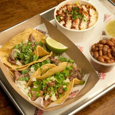 Steak tacos, with onions, cilantro, and served with Mexican corn, and beans.