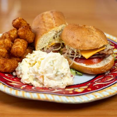 Club sandwich with sides of tater tots and coleslaw.