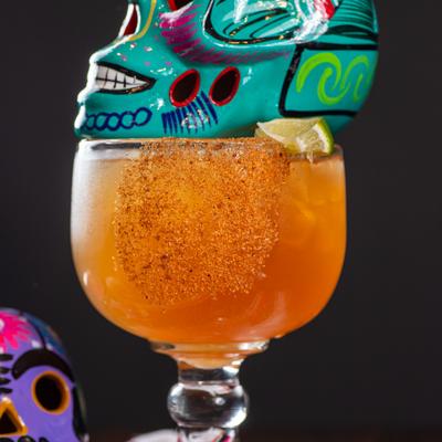 Tamarind Margarita served in a glass with a decorative skull topper.