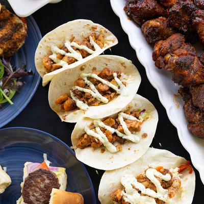 Chicken tacos drizzled with sauce, alongside other meals.