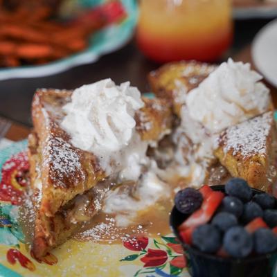 French toast topped with powdered sugar and whipped cream, served with berries.