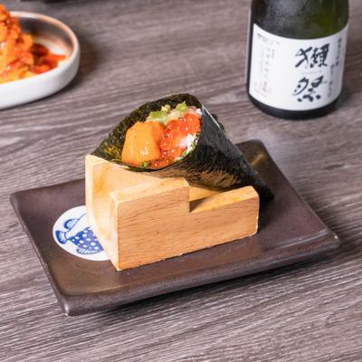Hand roll wrapped in seaweed, with sea urchin roe, shiso leaf, salmon roe, and wasabi.