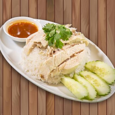 Tender cooked chicken served with rice, chili sauce, and cucumbers.