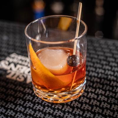 Glass of Old Fashioned rests on a bar mat.