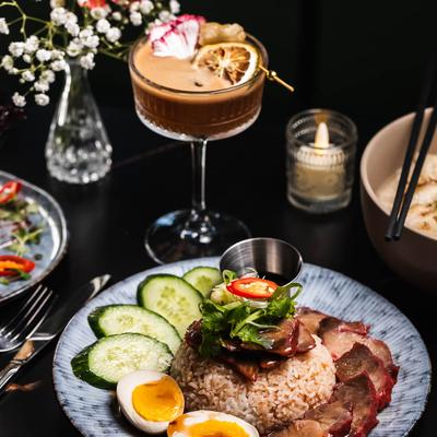 Rice topped with sliced meats, herbs and chilies, accompanied by a cocktail.