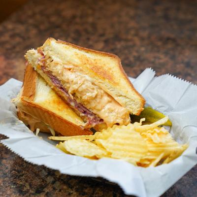 Corned beef sandwich with Swiss cheese, sauerkraut, 1000 Island dressing, and potato chips.