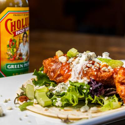 B's Taco accompanied with hot sauce bottles.