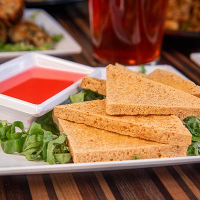 Crispy fried tofu triangles with bright red dipping sauce.
