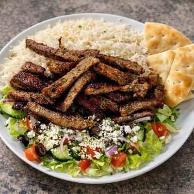 Lamb Gyro Plate served with rice, Greek pita bread, and side salad.