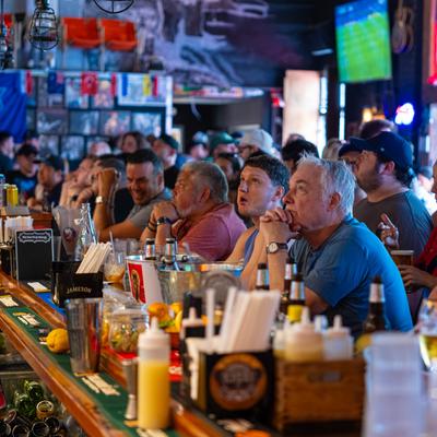 A crowded bar filled with patrons watching sports.