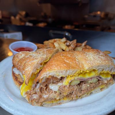 Philly Cuban sandwich served with fries and a dipping sauce.