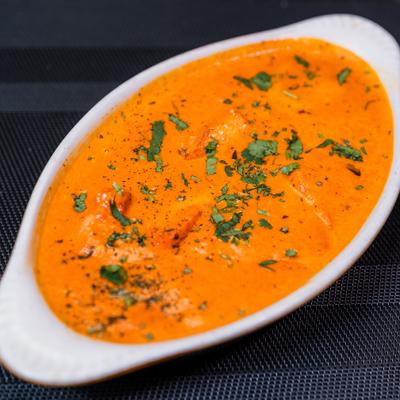 Butter Chicken garnished with fresh herbs.