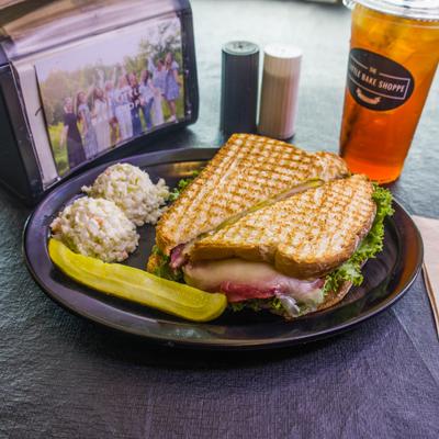 Sweet Bologna Sandwich on a grilled bread, served with a coleslaw and a pickle.