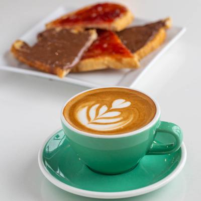 A cup of cappuccino served on the table with jam and Nutella toast