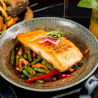 Grilled salmon fillet, served with cooked vegetables.