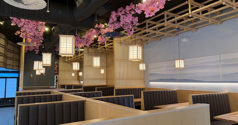 Interior - wooden booths, pink cherry blossoms, hanging lanterns, a mural on the wall