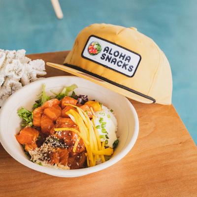 Farmer's Poke and Aloha Snacks cap on a table.
