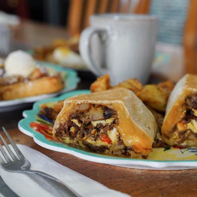 A burrito with smoked brisket, scrambled eggs, cheese, and smashed potatoes.