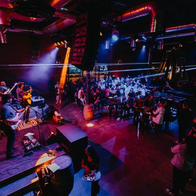 Interior featuring a live band playing on the stage and a crowd of people in the background.