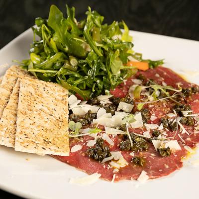 Beef carpaccio with capers and cheese shavings; a green arugula salad and sesame crackers.