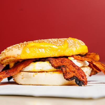 Breakfast bagel sandwich with a fried egg, bacon, and melted cheese.