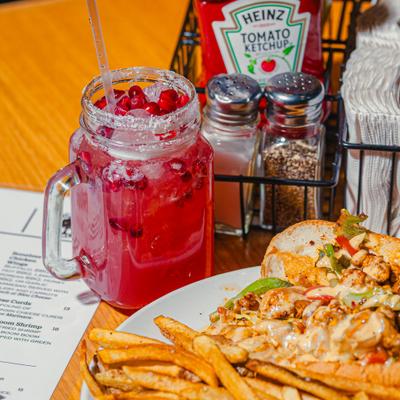 Cajun Chicken Philly with fries, and a  pomegranate drink on a dining table.