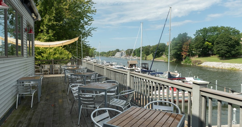 Outdoor restaurant deck - tables overlooking a marina filled with sailboats & motorboats.