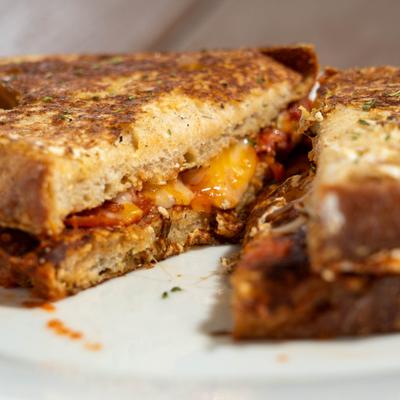 Sandwich with cold cuts, melted cheese, and tomato.
