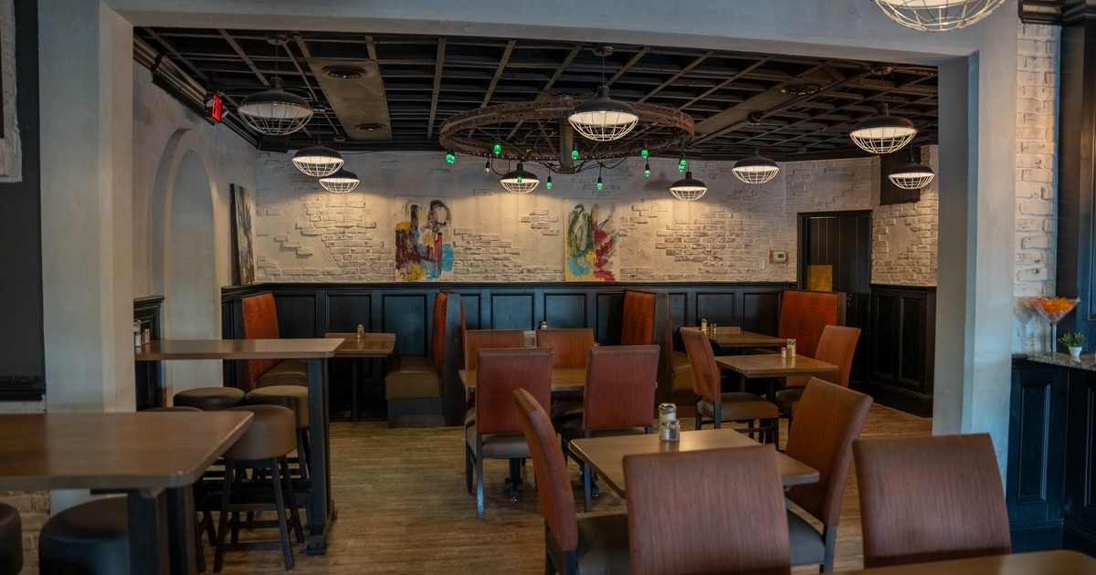 Inside, wooden tables, upholstered chairs, and white brick walls