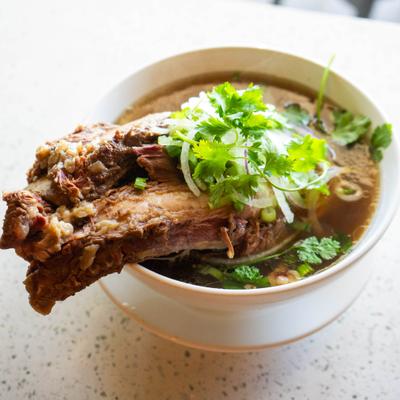 Beef rib pho, featuring a large, tender beef rib served in a flavorful broth.