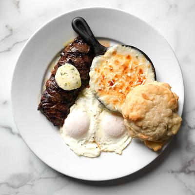 Brunch steak and eggs with grits and biscuit.