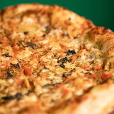 Margherita with pesto, tomato, fresh mozzarella, and basil, close-up.